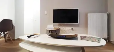 a living room with a white table and a tv at Athens' Secret Jewel by YHA in Athens