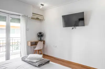 a white bedroom with a tv on the wall at Lovely 2 bedroom rental in excellent location in Athens
