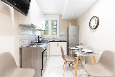 a kitchen with a table and chairs and a clock on the wall at AIOLOS LUXURY alimos kalamaki market apartment 3 near the sea in Athens