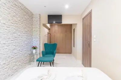 a bedroom with a green chair and a brick wall at AIOLOS LUXURY alimos kalamaki market apartment 3 near the sea in Athens