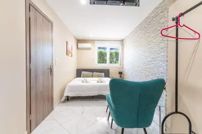 a bedroom with a bed and a green chair at AIOLOS LUXURY alimos kalamaki market apartment 3 near the sea in Athens