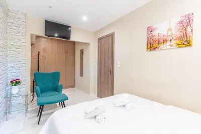 a bedroom with a white bed and a blue chair at AIOLOS LUXURY alimos kalamaki market apartment 3 near the sea in Athens