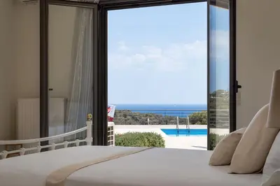 a bedroom with a bed and a view of the ocean at Aphaia Villa & Residences Aegina in Agia Marina Aegina