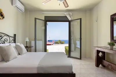 a bedroom with a bed and a view of the ocean at Aphaia Villa & Residences Aegina in Agia Marina Aegina
