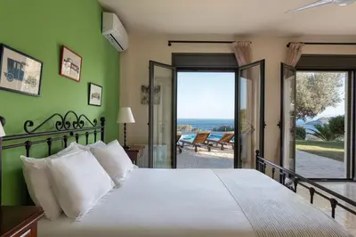 a bedroom with a bed with a view of the ocean at Aphaia Villa & Residences Aegina in Agia Marina Aegina