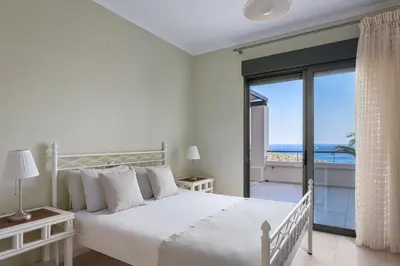 a bedroom with a bed with a view of the ocean at Aphaia Villa & Residences Aegina in Agia Marina Aegina