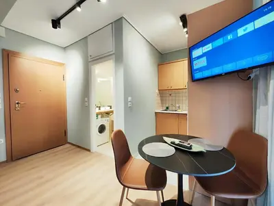 a living room with a table and chairs and a television at Veno Donwtown in Athens