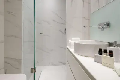 a white bathroom with a sink and a shower at Kalypso, Urban Apartment with Unique Views of The Acropolis! in Athens
