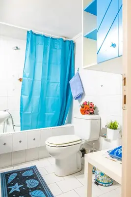 a bathroom with a toilet and a blue shower curtain at Sunny Apartment in Athens