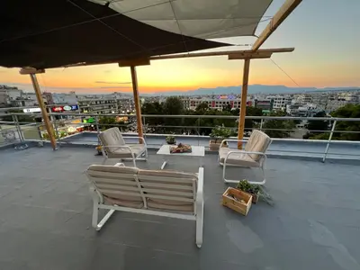 a rooftop patio with chairs and a view of a city at Square's View Agia Paraskevi in Athens