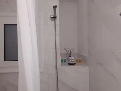 a white bathroom with a shower and a window at Stylish apartment in Athens