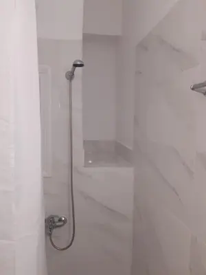a shower in a bathroom with white tiles at Stylish apartment in Athens