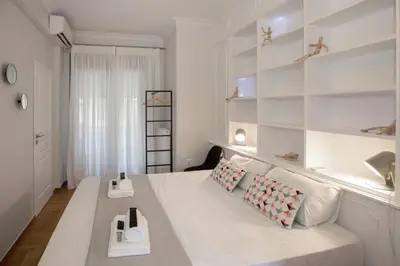 a bedroom with a bed with white walls and shelves at Syntagma Apartments with Acropolis view in Athens