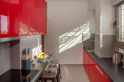 a kitchen with red cabinets and a bowl of fruit on the counter at Syntagma Apartments with Acropolis view in Athens