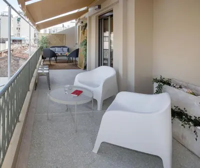 a balcony with white chairs and a table at Syntagma Apartments with Acropolis view in Athens
