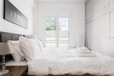 a white bedroom with a large white bed with white pillows at Diogenis' Jug in Athens