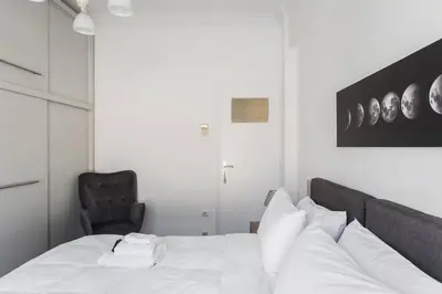 a bedroom with a bed with white sheets and a chair at Diogenis' Jug in Athens