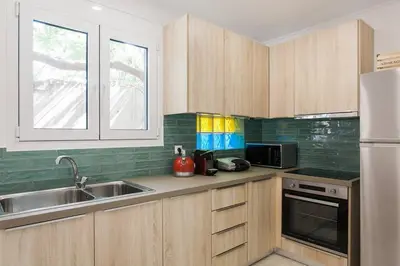 a kitchen with wooden cabinets and a sink and a refrigerator at Diogenis' Jug in Athens
