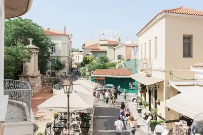 people walking down a street with tables and umbrellas at Diogenis' Jug in Athens