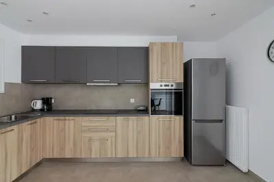 a kitchen with wooden cabinets and a stainless steel refrigerator at Renovated Apartment next to Panathenaic Stadium in Athens