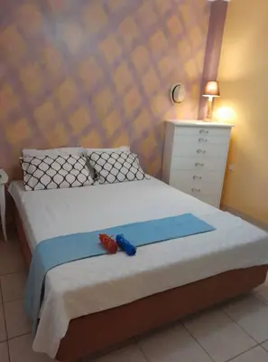 a bedroom with a bed with two slippers on it at PARADISE in Dhaskalión