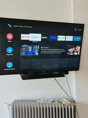 a flat screen tv hanging on a wall with a radiator at Penthouse spacious w super wifi & terrace, 2 min from metro in Athens