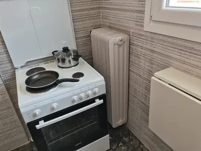 a kitchen with a stove with a pot and pans on it at Penthouse spacious w super wifi & terrace, 2 min from metro in Athens
