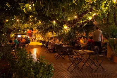 a group of people sitting at tables in a garden at night at Penthouse spacious w super wifi & terrace, 2 min from metro in Athens