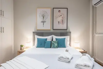 a bedroom with a large white bed with blue pillows at Elegant Mavili Suite by CloudKeys in Athens
