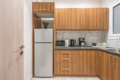 a kitchen with a white refrigerator and wooden cabinets at Elegant Mavili Suite by CloudKeys in Athens