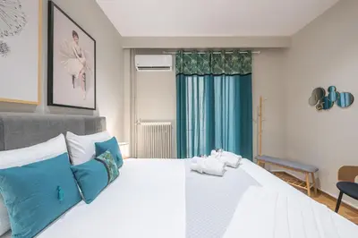 a bedroom with a large white bed with blue pillows at Elegant Mavili Suite by CloudKeys in Athens