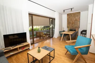 a living room with a flat screen tv and a blue chair at AthensBlues Glyfada Premium in Athens
