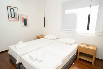 a white bedroom with a bed and a window at AthensBlues Glyfada Premium in Athens