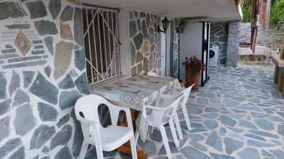 a table and chairs on a patio with a stone wall at SHLEY House 1 in Artemida