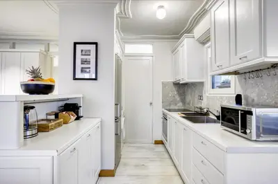 a white kitchen with white cabinets and a sink at Monastiraki Stylish Loft W/ Acropolis View/Bathtub in Athens