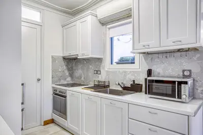a white kitchen with a sink and a microwave at Monastiraki Stylish Loft W/ Acropolis View/Bathtub in Athens