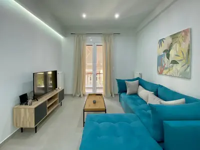 a living room with a blue couch and a tv at Luxury 1 Bedroom Flat in Athens