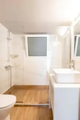 a white bathroom with a toilet and a sink at Flisvos Marina refurbished apartment in Athens