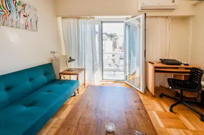 a living room with a blue couch and a desk at 5th Floor Boho Quircky in Athens