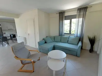 a living room with a blue couch and a table at Andi's Studio Porto Rafti in Porto Rafti