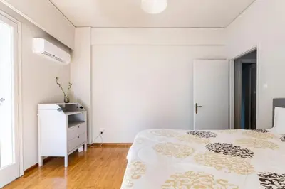 a white bedroom with a bed and a dresser at Spacious renovated flat in the Athens Riviera in Athens