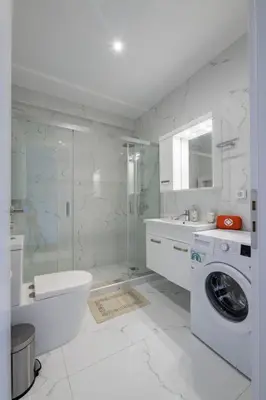 a white bathroom with a shower and a washing machine at Lush Emerald apt steps from Acropolis & Plaka! in Athens