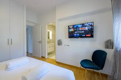 a bedroom with a white bed and a blue chair at Lush Emerald apt steps from Acropolis & Plaka! in Athens