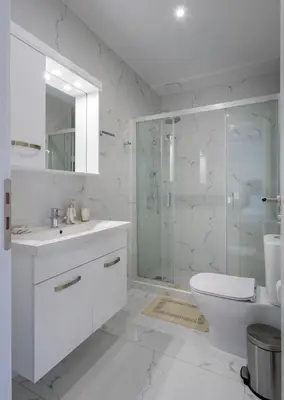 a white bathroom with a glass shower and a toilet at Lush Emerald apt steps from Acropolis & Plaka! in Athens