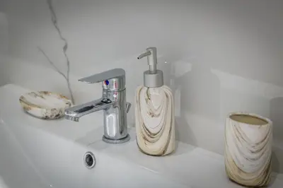 a bathroom sink with a soap dispenser next to a faucet at Lush Emerald apt steps from Acropolis & Plaka! in Athens