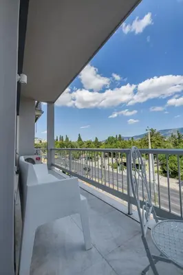 a white bench sitting on a balcony with a view at Lush Emerald apt steps from Acropolis & Plaka! in Athens