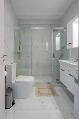 a white bathroom with a glass shower and a toilet at Lush Emerald apt steps from Acropolis & Plaka! in Athens