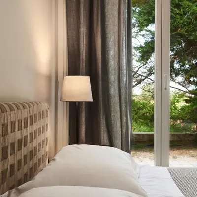 a bed with a lamp in front of a window at Varaba Country House in Markopoulo