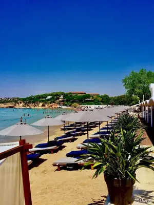 a beach with chairs and umbrellas and people in the water at Villa Hermes in Vouliagmeni