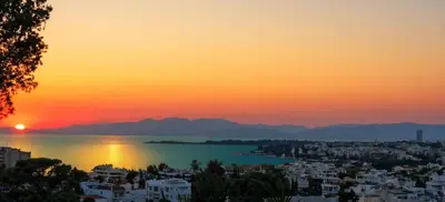 a view of a city with the sunset in the background at Villa Hermes in Vouliagmeni
